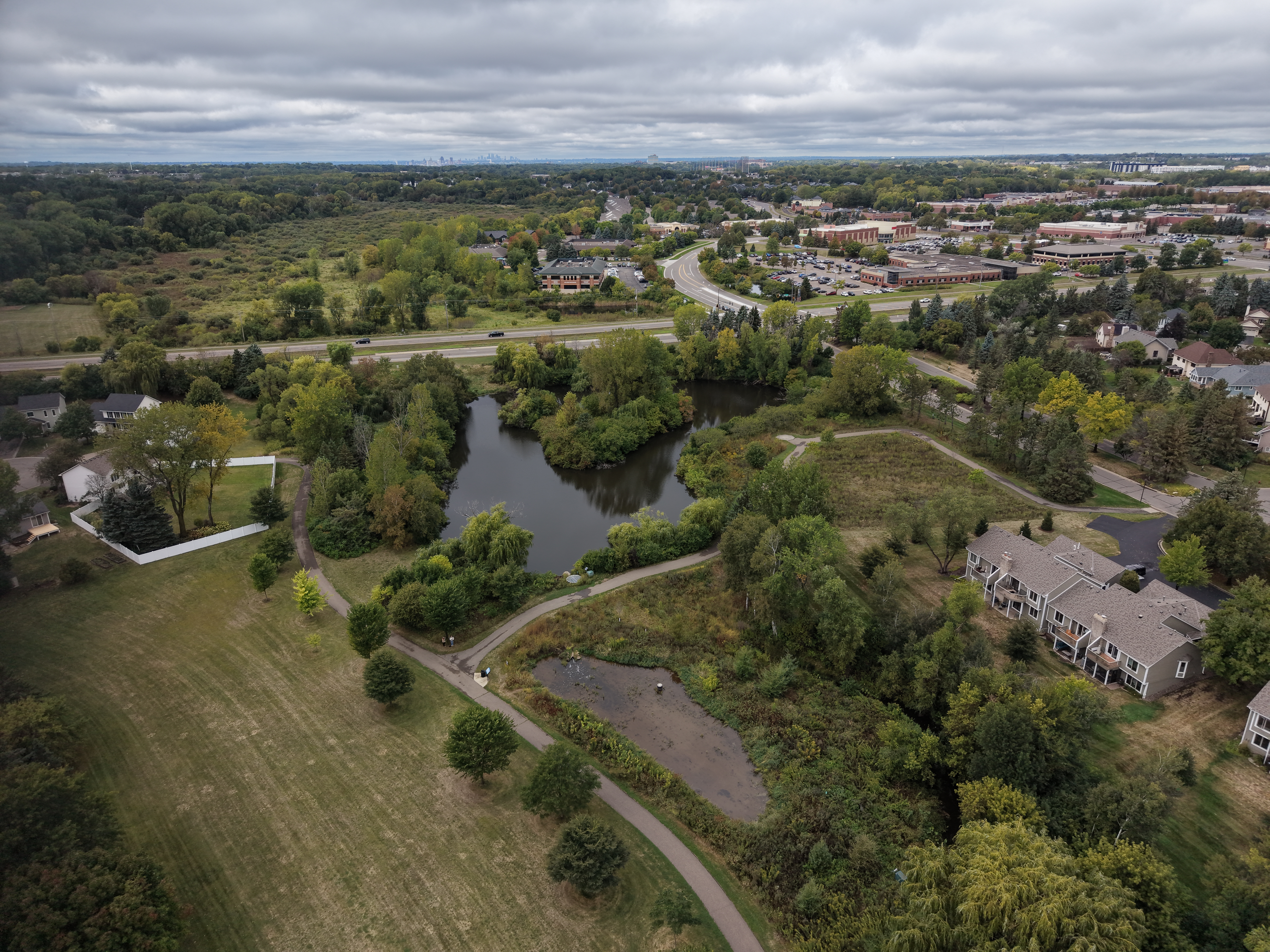 Aerial view of a small pond and paved trails in a neighborhood