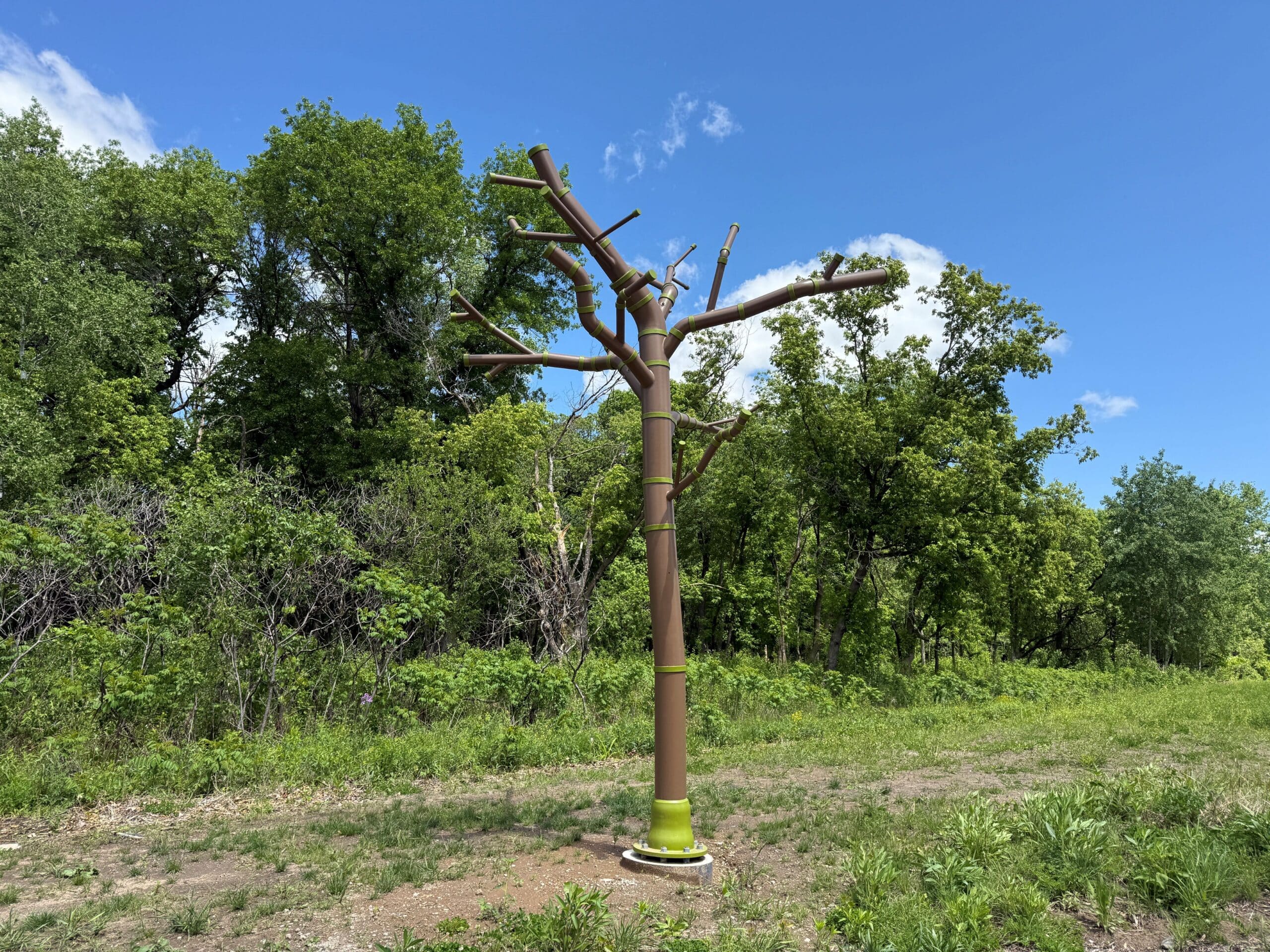 A sculpture in the shape of a tree built with water piping and painted in brown and green
