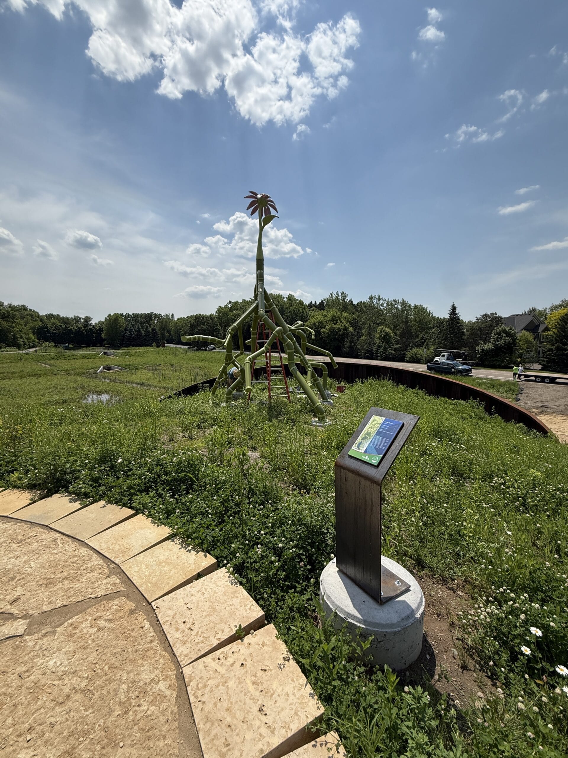 A sculptural flower built from stormwater pipe and painted in green and pink