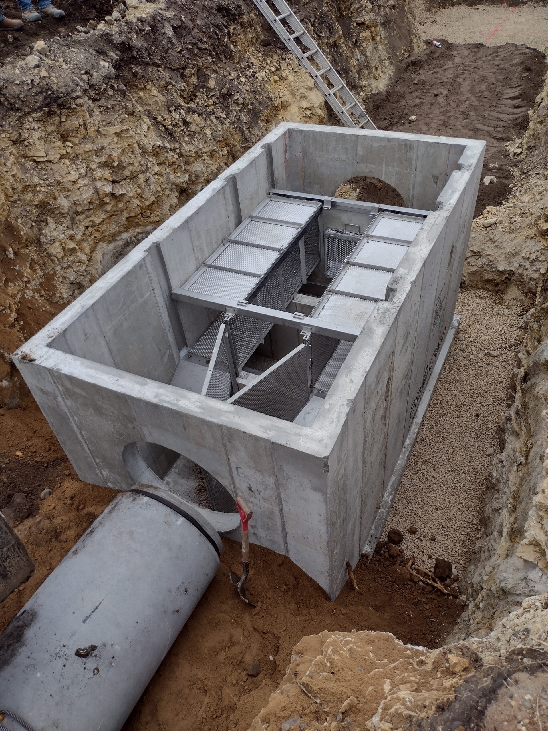 Large concrete box with interior chambers submerged in the ground during construction
