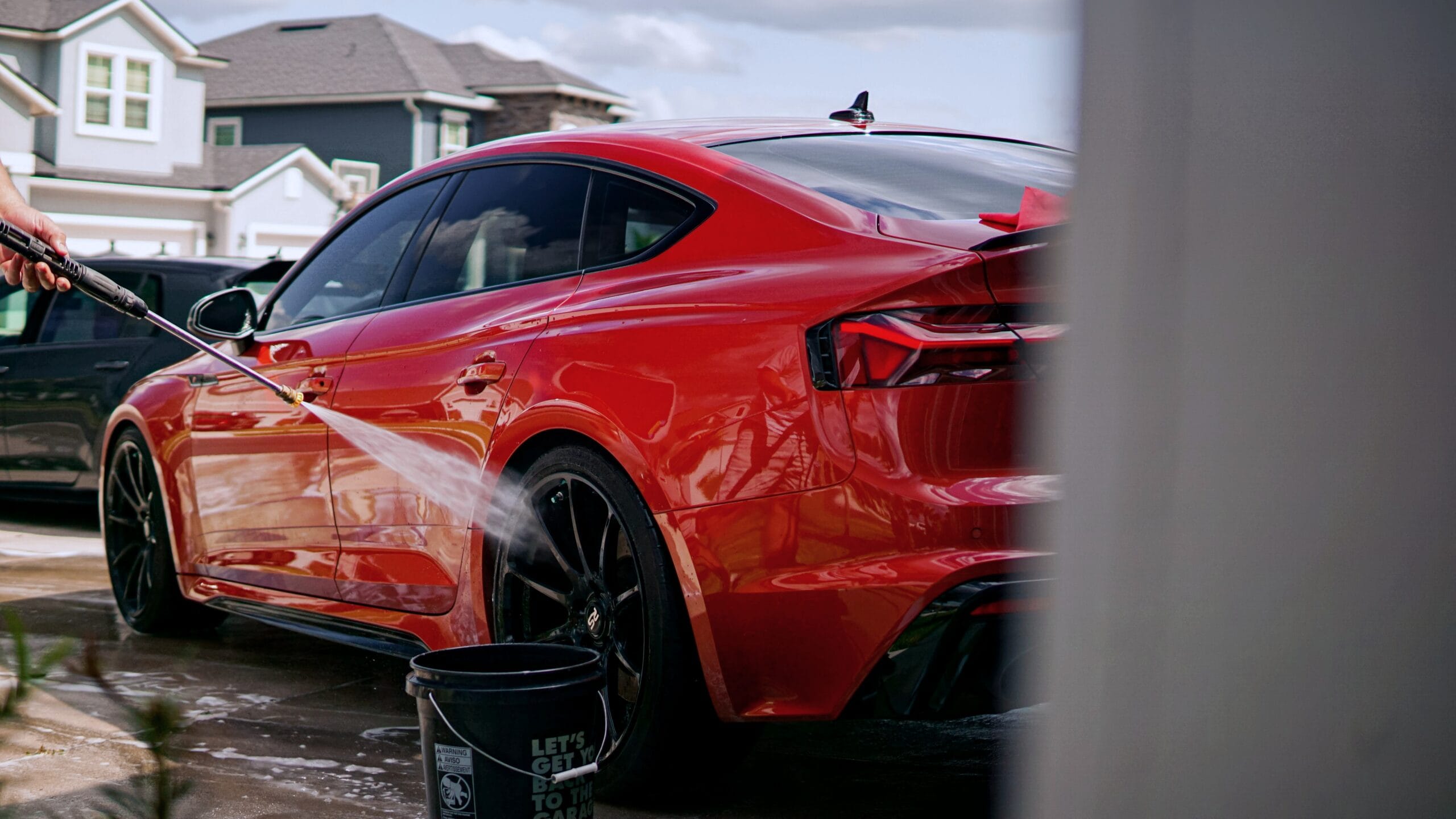 Car in driveway being washed by hand