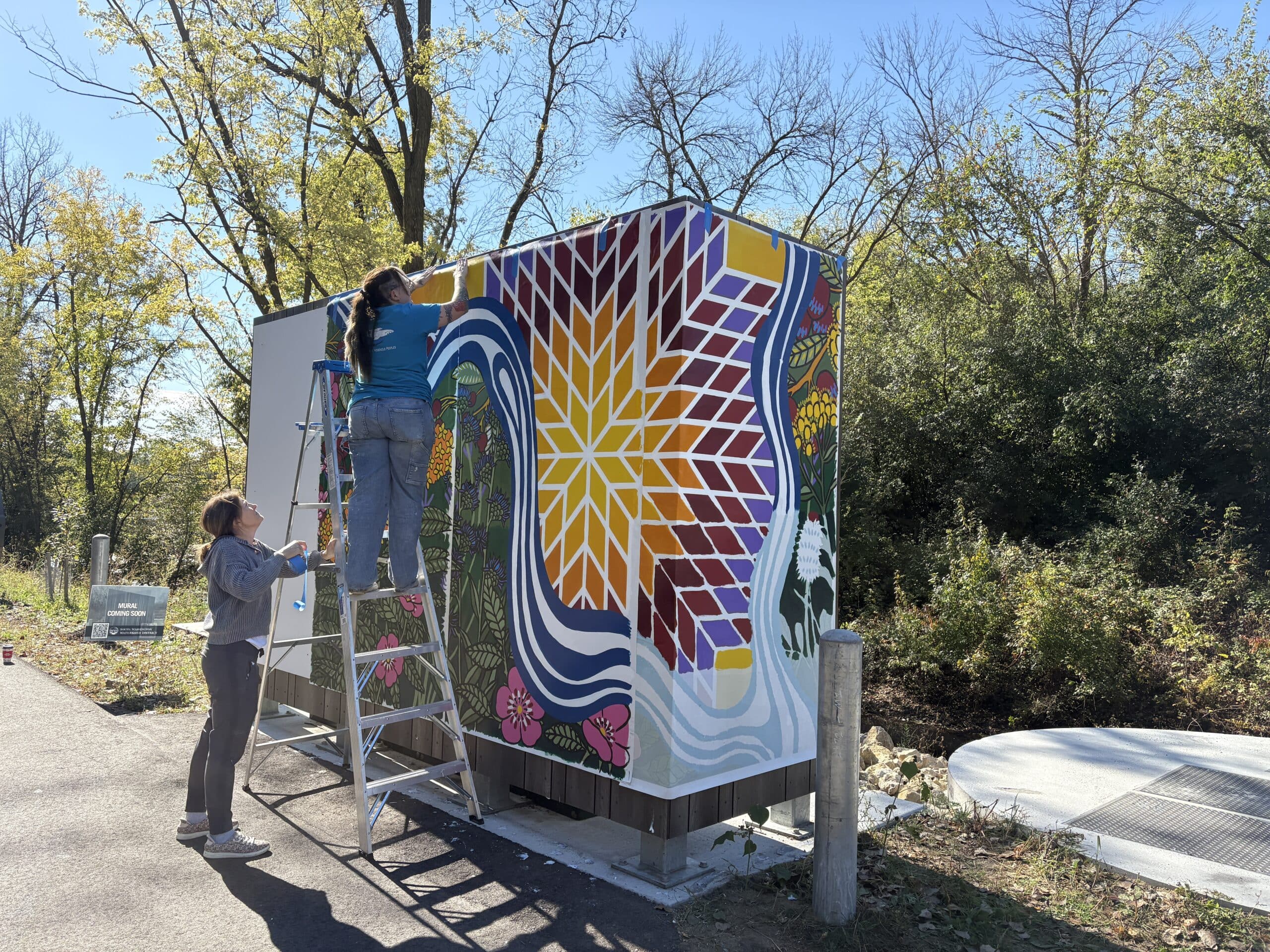Person on a ladder applying glue to a vertical surface