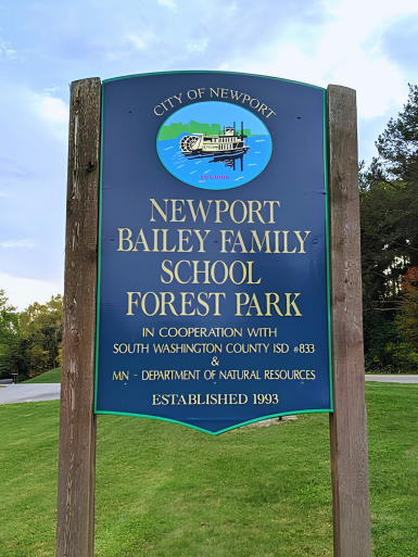 Park entry sign that reads "Newport Bailey Family School Forest Park in cooperation with South Washington County ISD #883 & Minnesota Department of Natural Resources. Established 1993"