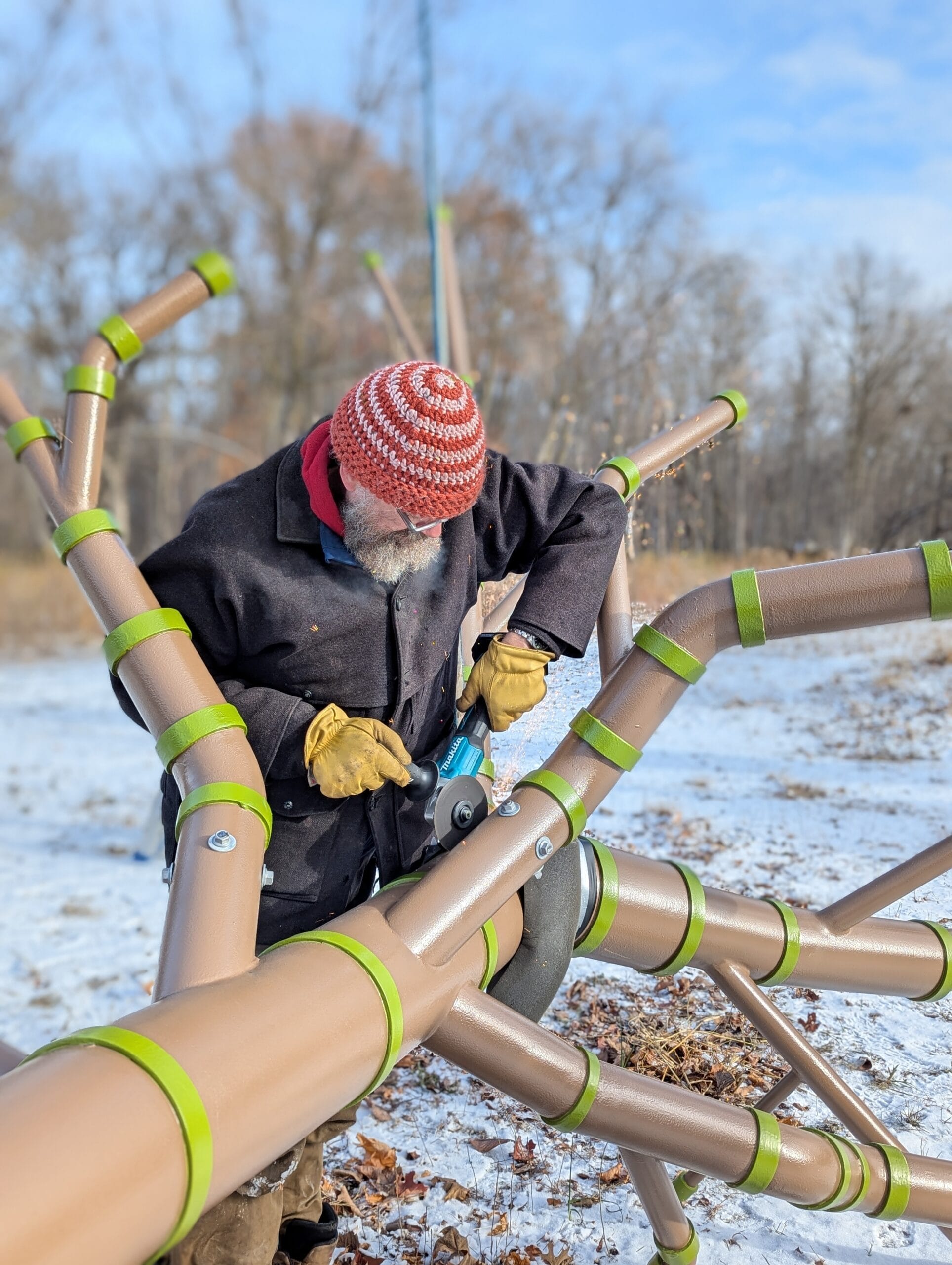 Person using hand tools on metal pipes painted to look like a tree