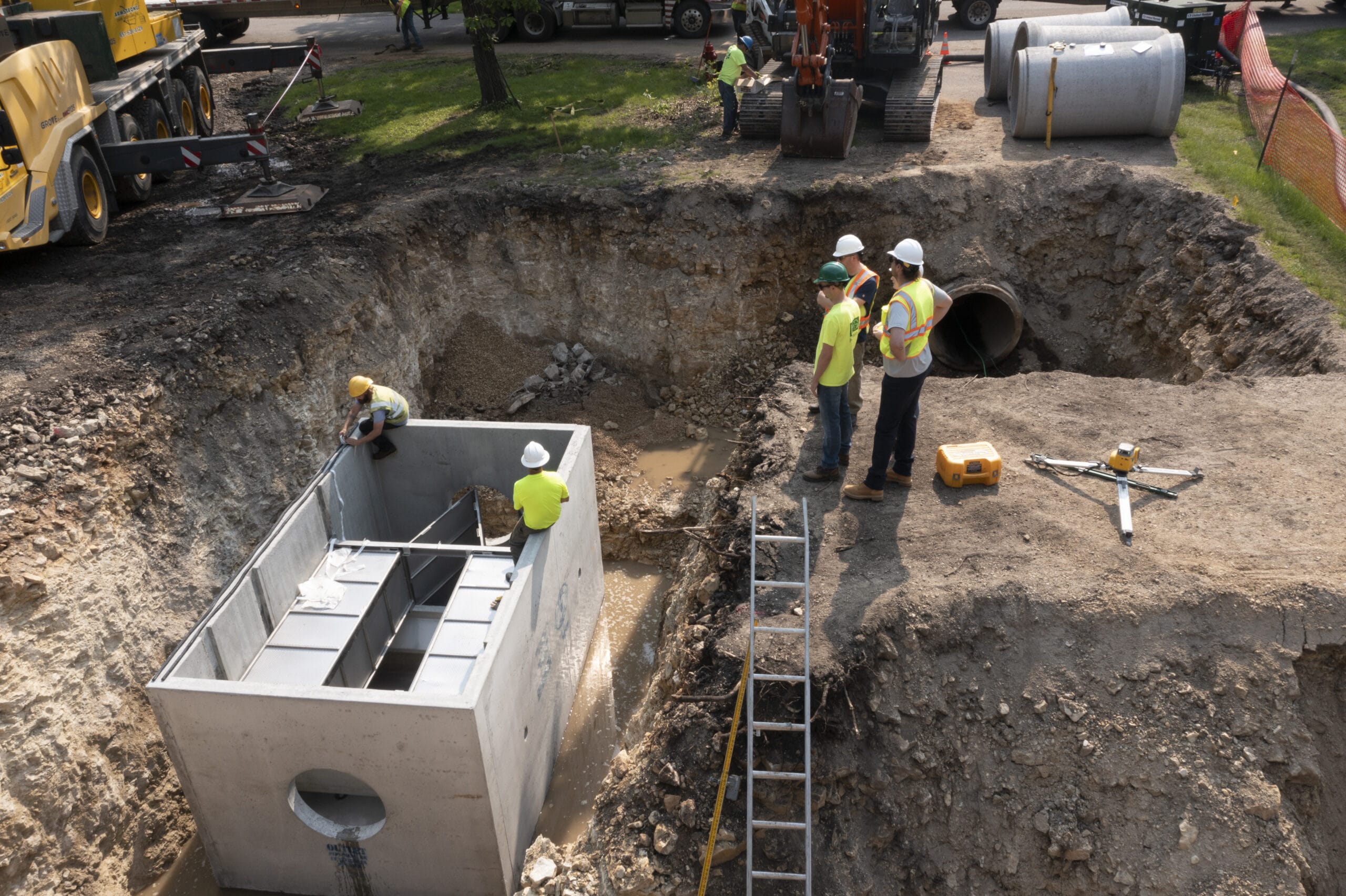 Construction crews installing a large concrete box while other construction works look on